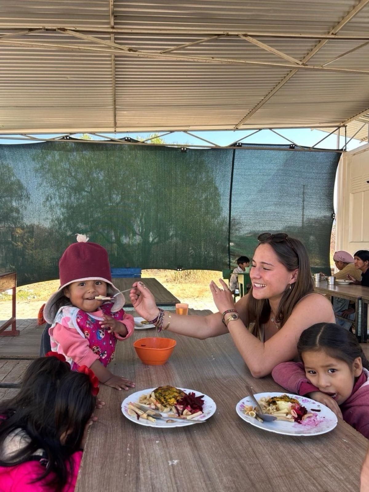 Une bénévole donne à manger à une petite fille au comedor de Cochabamba